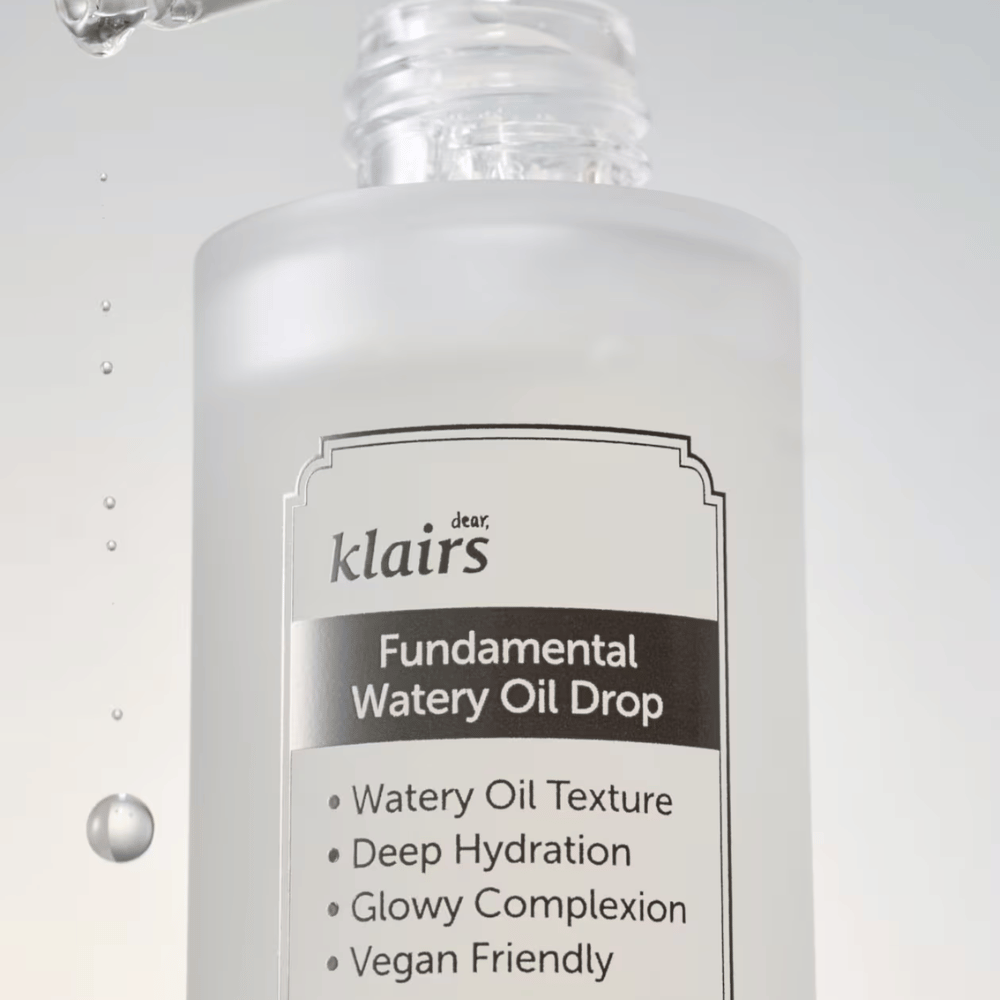 Gros plan sur le flacon Klairs Fundamental Watery Oil Drop, avec un texte soulignant les caractéristiques du produit telles que "Texture d'Huile Aqueuse", "Hydratation Profonde", "Teint Lumineux" et "Amical pour les Végans".
