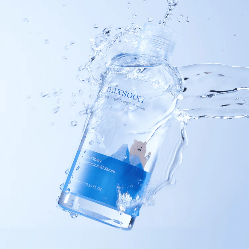 Mixsoon Glacier Water Hyaluronic Acid Serum-bouteille avec une étiquette bleue et un motif d'ours polaire entourée d'éclaboussures d'eau sur fond bleu clair.