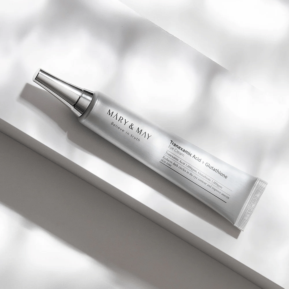 Gros plan de Mary&May Tranexamic Acid + Glutathione Eye Cream avec applicateur métallique, développé pour éclaircir les cernes et unifier le teint autour des yeux.