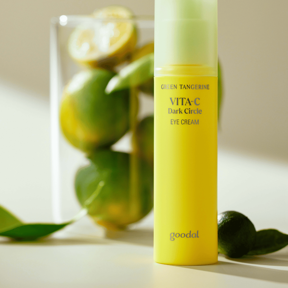 Une bouteille Goodal Green Tangerine Vita C Dark Circle Eye Cream 30ml sur une table à côté d'un citron vert.