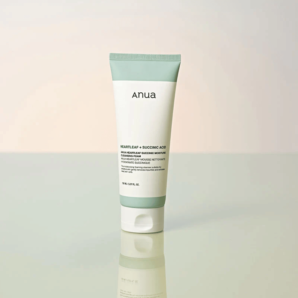 Image de produit isolée de Anua Heartleaf + Succinic Acid Moisture Cleansing Foam. Le produit est présenté debout sur une surface réfléchissante qui met clairement en valeur le design de l’emballage et l’esthétique épurée de la marque.