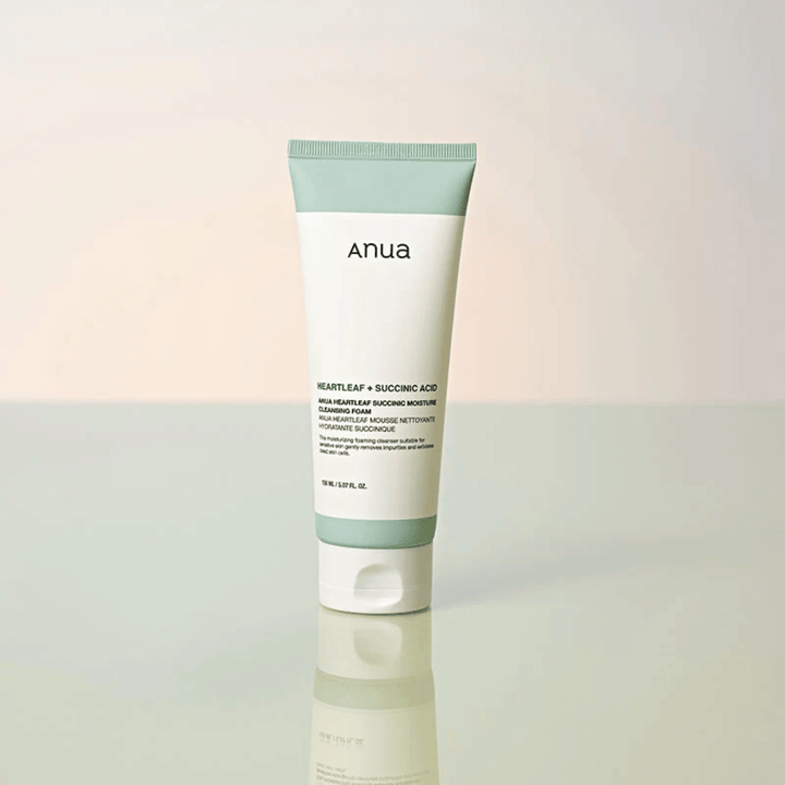 Image de produit isolée de Anua Heartleaf + Succinic Acid Moisture Cleansing Foam. Le produit est présenté debout sur une surface réfléchissante qui met clairement en valeur le design de l’emballage et l’esthétique épurée de la marque.