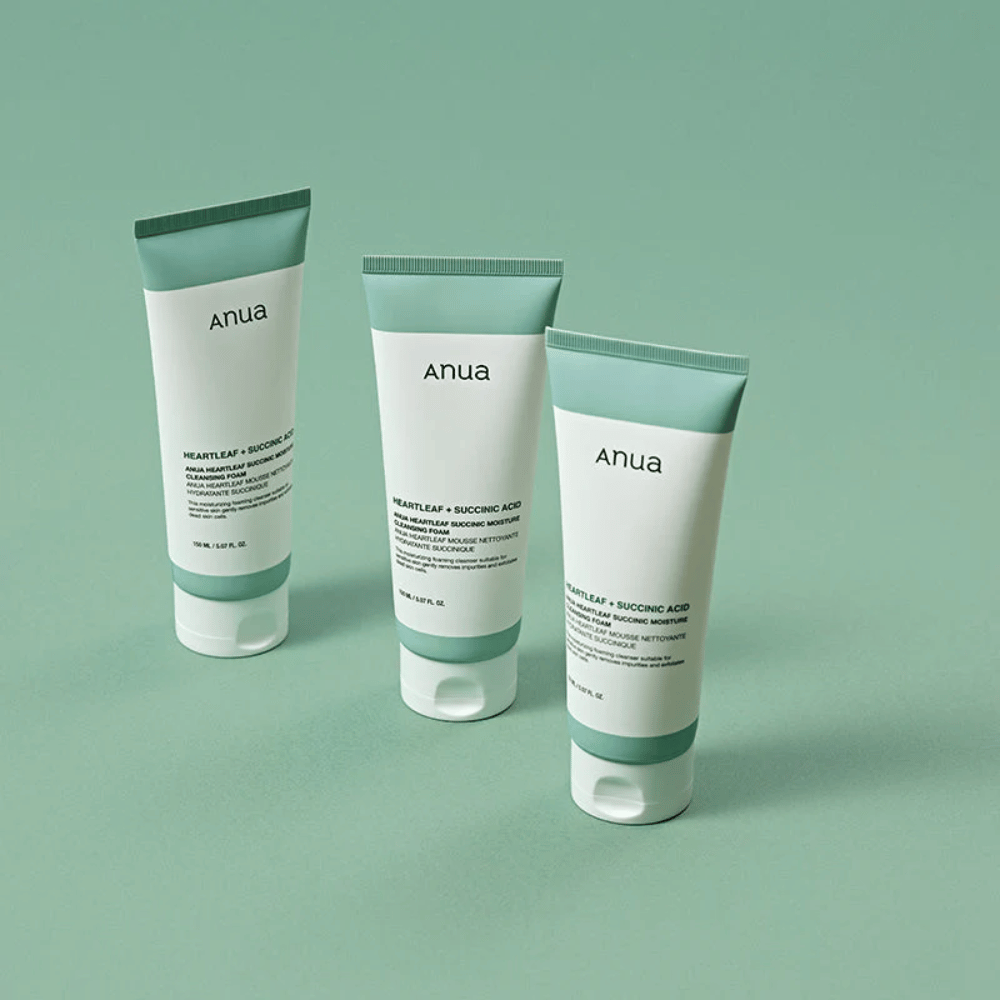 Trois emballages de Anua Heartleaf + Succinic Acid Moisture Cleansing Foam présentés sur un fond vert clair. L’image met en avant le design propre et minimaliste du produit tout en donnant une impression professionnelle de la gamme de produits.