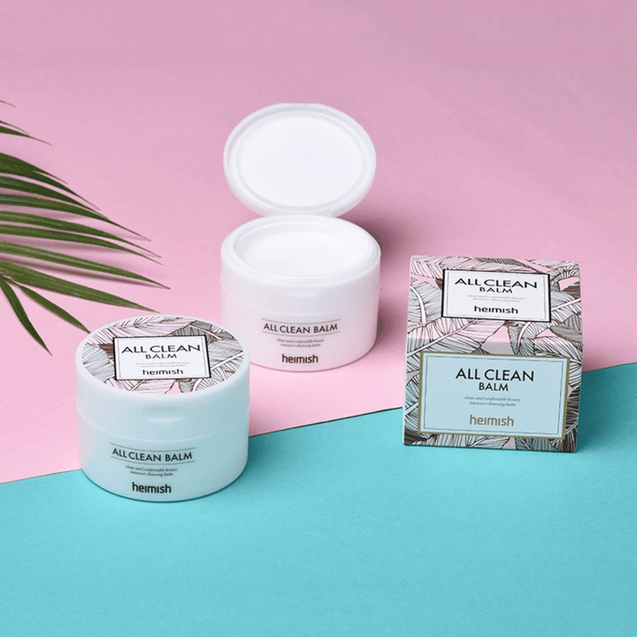 Heimish All Clean Balm 120ml et une paume sur fond rose et bleu, adapté aux peaux sensibles.