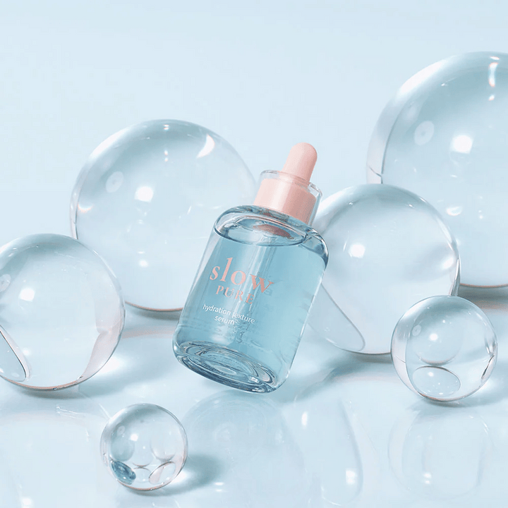 Slow Pure Hydration Texture Serum placée parmi des bulles transparentes, symbole d'hydratation intense.