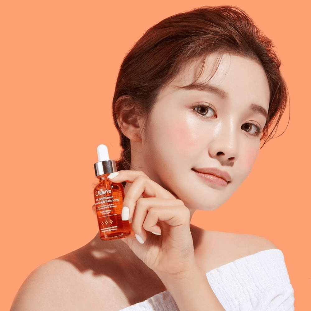 Une femme tenant une bouteille de JUMISO All Day Vitamin Brightening & Balancing Facial Serum 30ml.