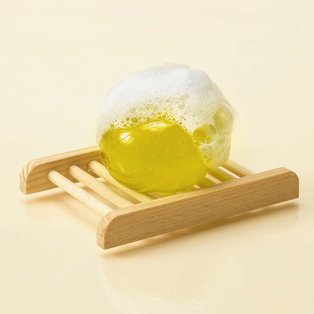 Moussant Ongredients Jeju Cica Cleansing Ball sur porte-savon – nettoyage doux qui renforce la barrière cutanée et réduit l'irritation.