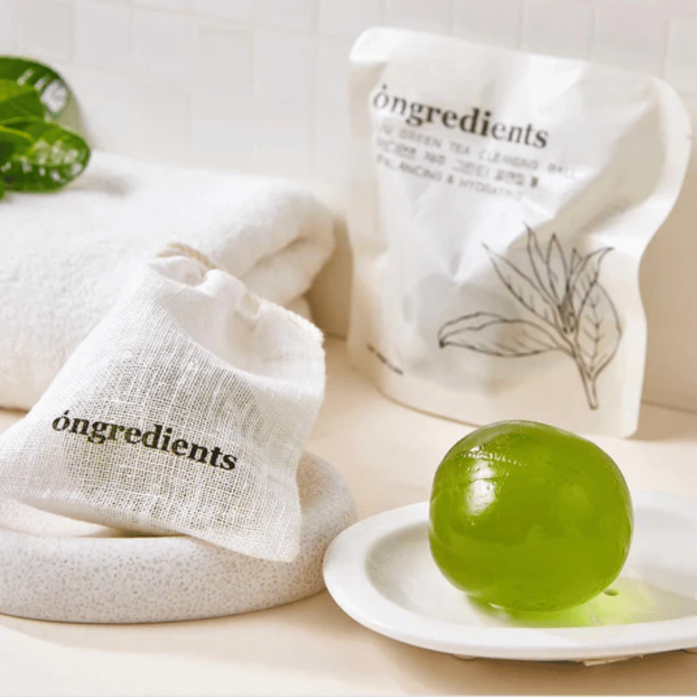 Óngredients Jeju Green Tea Cleansing Ball placé sur une assiette avec emballage et serviette – nettoyage doux avec thé vert de Jeju.