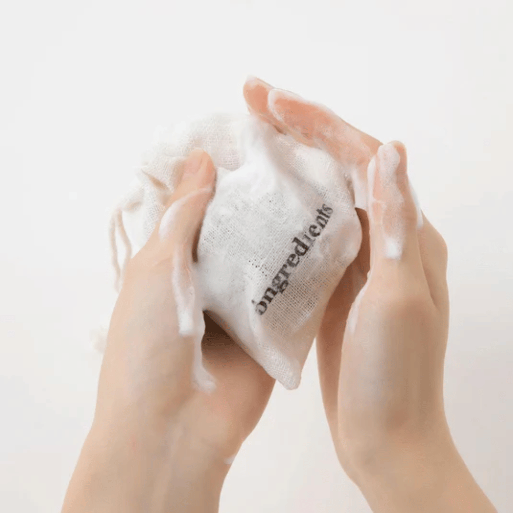 Mains qui font mousser Óngredients Jeju Green Tea Cleansing Ball dans un sac en tissu – nettoyant facial vegan au thé vert.