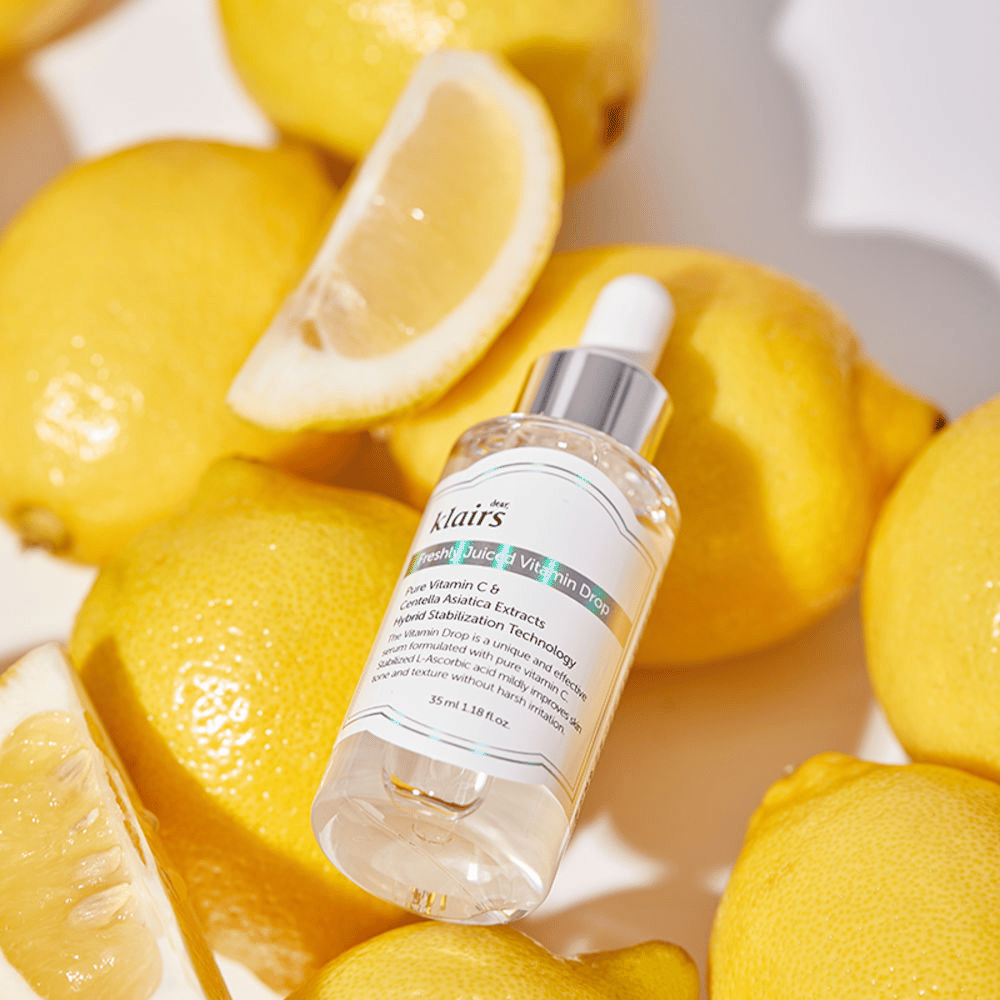 Klairs Freshly Juiced Vitamin Drop flacon de sérum entouré de moitiés de citron frais et de tranches de citron sur une surface claire, mettant en avant les ingrédients.