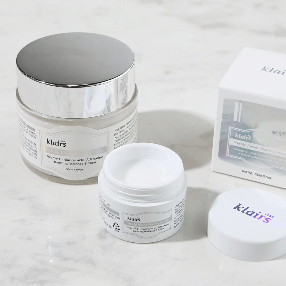 Une collection de produits de soin de la peau de Klairs sur un banc en marbre : un pot fermé, un pot ouvert avec de la crème, et une boîte avec du texte.