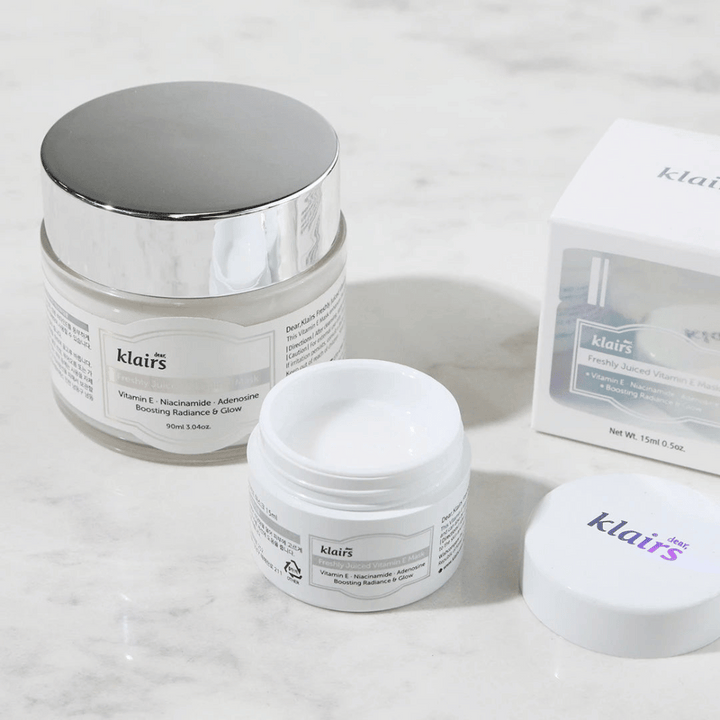 Une collection de produits de soin de la peau de Klairs sur un banc en marbre : un pot fermé, un pot ouvert avec de la crème, et une boîte avec du texte.