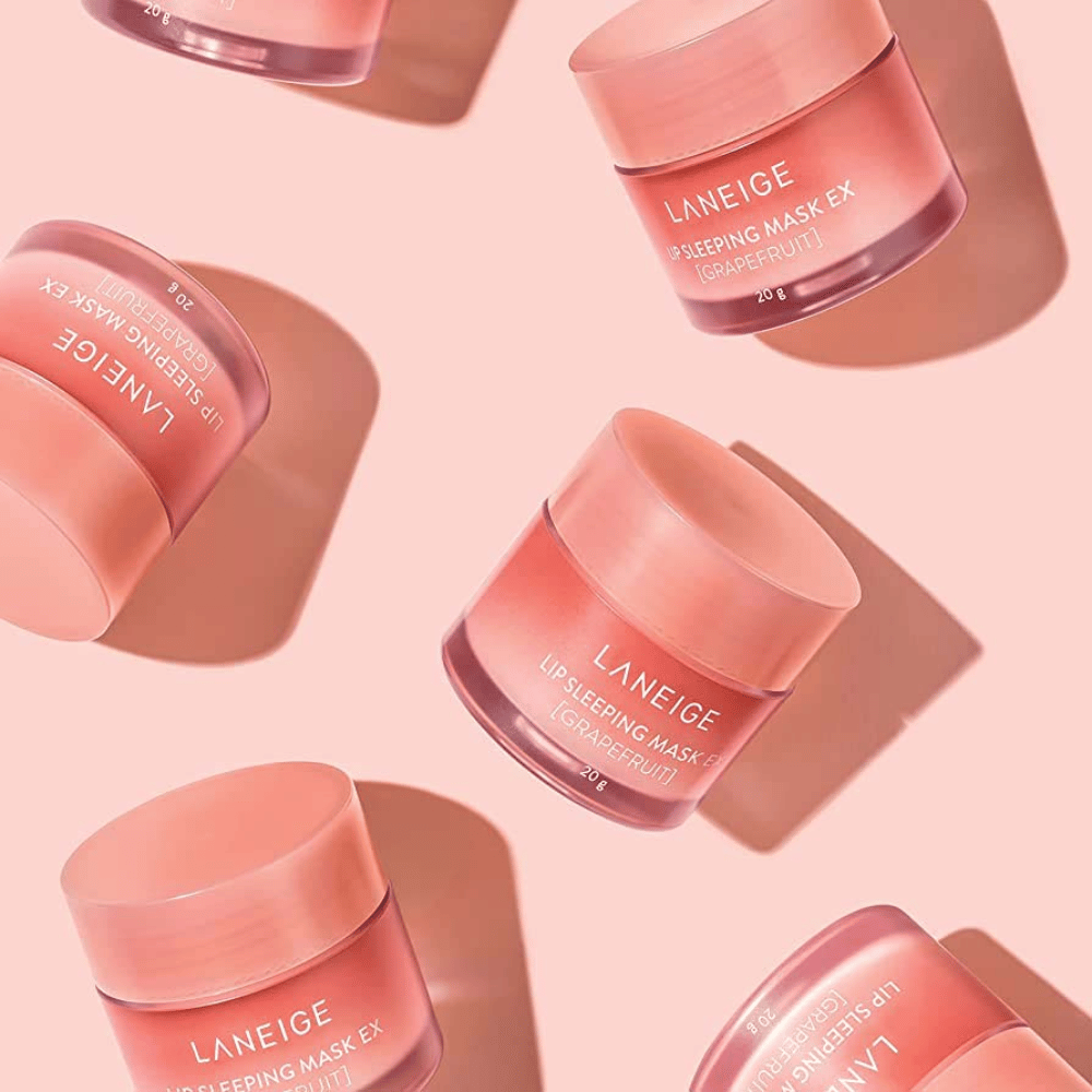 Quatre pots LANEIGE Lip Sleeping Mask Pamplemousse 20g sur fond rose, favorise le pamplemousse et l'hydratation.