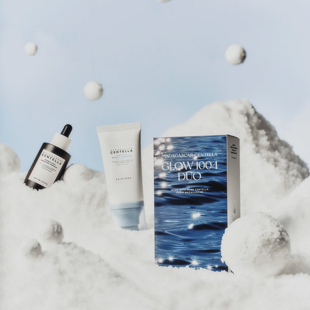 L'image montre le kit de soins de la peau "Madagascar Centella Glow 1004 Duo" de SKIN1004, placé sur un fond représentant de la neige et le ciel.