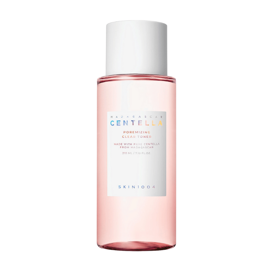 Une bouteille avec Madagascar Centella Poremizing Clear Toner, qui est transparente avec une teinte rose. Le produit a un bouchon blanc et une étiquette avec le texte "Poremizing Clear Toner" et "Made with Pure Centella from Madagascar." La bouteille contient 210 ml et donne une sensation de fraîcheur et de soin de la peau.