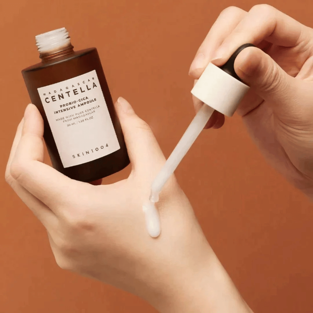 Mains utilisant une pipette pour doser "Madagascar Centella Probio-Cica Intensive Ampoule" de SKIN1004.