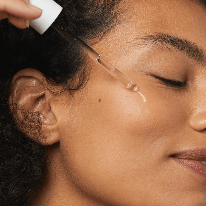 Femme appliquant Skin1004 Madagascar Centella Hyalu-Cica First Ampoule sur la joue avec une pipette.