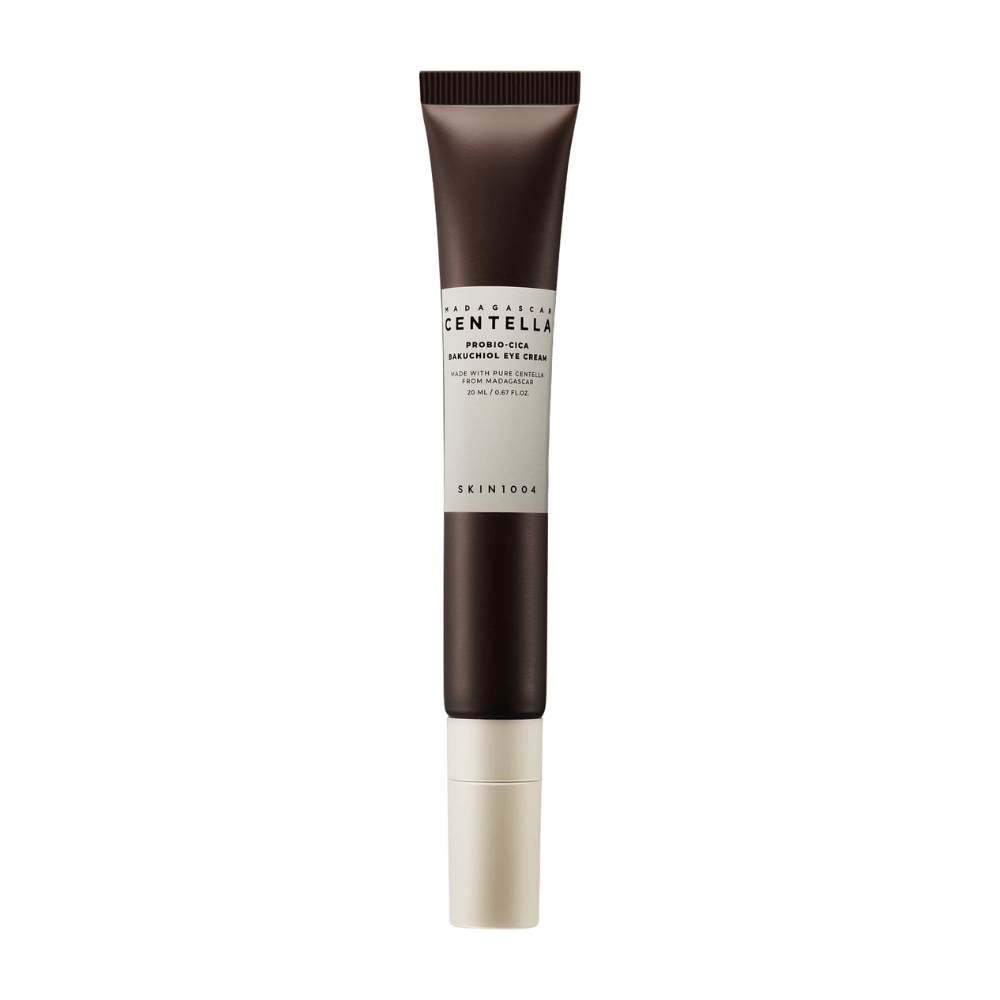 Un tube de "Madagascar Centella Probio-Cica Bakuchiol Eye Cream" de SKIN1004. Le produit est conçu pour la zone des yeux et contient des ingrédients tels que la centella de Madagascar et le bakuchiol, connus pour leurs propriétés de soin de la peau et d'hydratation. Le tube est élégant avec une couleur brun foncé passant au blanc.
