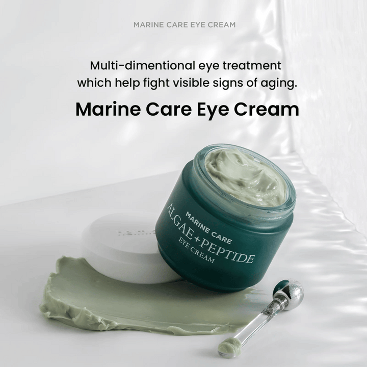 Heimish Marine Care Algae + Peptide Eye Cream dans un pot ouvert avec une crème verdâtre. La crème est étalée à côté du pot et un applicateur est posé à côté. Le produit combat les signes de l'âge et offre une hydratation intense.