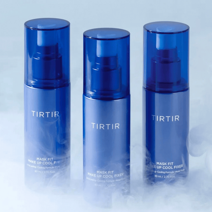 Trois flacons pulvérisateurs bleus avec "TIRTIR Mask Fit Make Up Cool Fixer" sur l'étiquette. Chaque flacon contient 80 ml (2,70 fl. oz.) et est conçu pour offrir une sensation rafraîchissante et un maquillage durable. Les flacons sont posés sur un fond clair avec de la brume pour créer une atmosphère de fraîcheur.