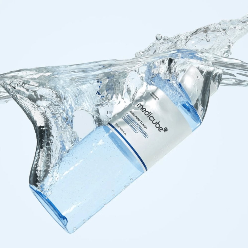 Medicube Zero Pore Toner 250 ml, toner visage exfoliante avec AHA, BHA et PHA. Flacon bleu transparent entouré d’une grande éclaboussure d’eau.