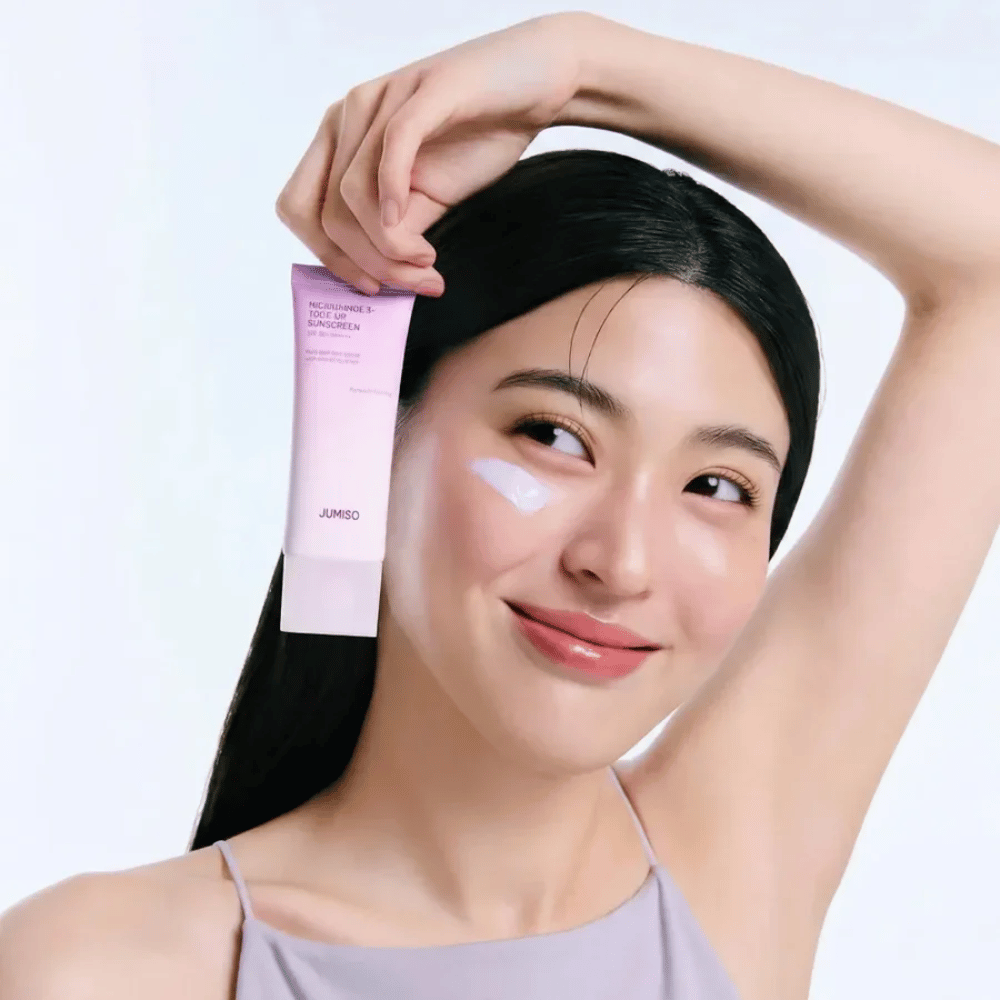 Le modèle tient JUMISO Niacinamide 3+ Tone-Up Sunscreen SPF50+ PA++++ – une crème solaire à la niacinamide qui unifie le teint et protège la peau.