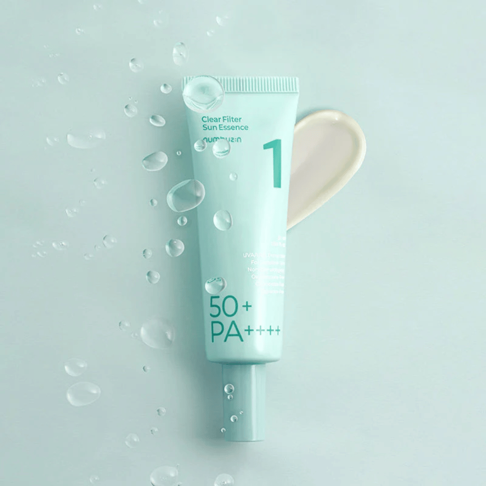 Un tube bleu clair avec No.1 Clear Filter Sun Essence SPF 50+ PA++++. Le tube est décoré de gouttelettes d'eau et une noisette du produit est montrée à côté. Le produit est conçu pour offrir un facteur de protection solaire élevé et une protection contre les rayons UVA/UVB.