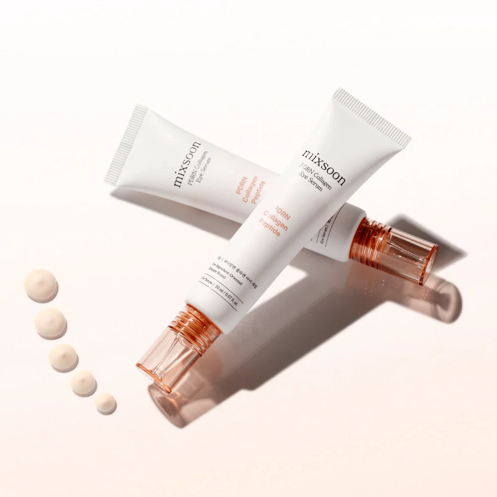 Deux tubes de Mixsoon PDRN Collagen Eye Serum sont croisés avec de petites gouttes de sérum. Un soin léger pour les yeux qui hydrate et lisse les lignes.