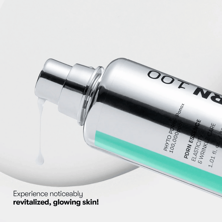 Gros plan sur une bouteille à pompe argentée avec VT PDRN Essence 100. Une essence blanche coule de l'embout, et le texte sur l'image indique : "Découvrez une peau visiblement revitalisée et éclatante !"