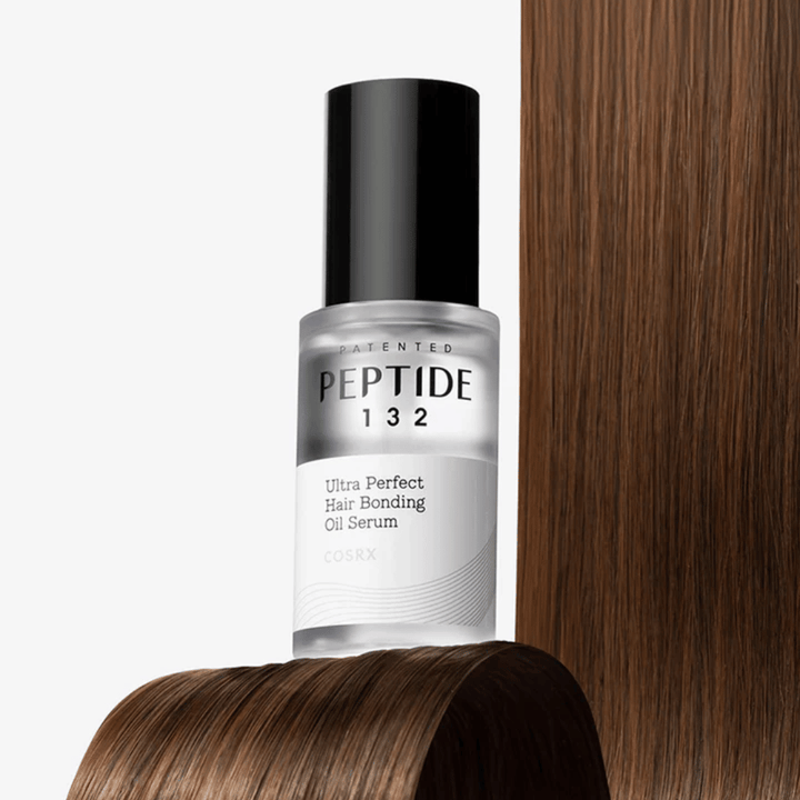 COSRX Peptide 132 Ultra Perfect Hair Bonding Oil Serum placée contre des cheveux brillants – offre force, douceur et brillance.
