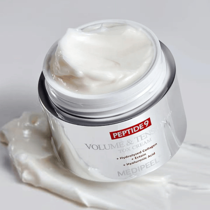 Gros plan sur MEDI-PEEL Peptide 9 Volume & Tension Tox Cream. La crème riche contient du collagène hydrolysé, de l'ectoïne et de l'acide hyaluronique pour une peau plus ferme et hydratée.