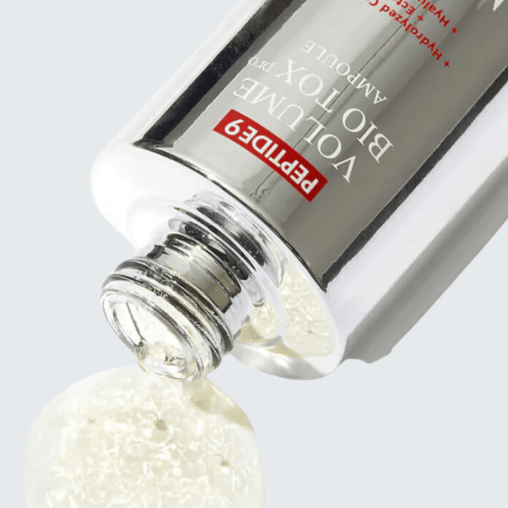 Gros plan sur MEDI-PEEL Peptide 9 Volume Bio Tox Pro Ampoule en train d'être versé. La formule claire avec collagène, ectoïne et acide hyaluronique hydrate en profondeur.