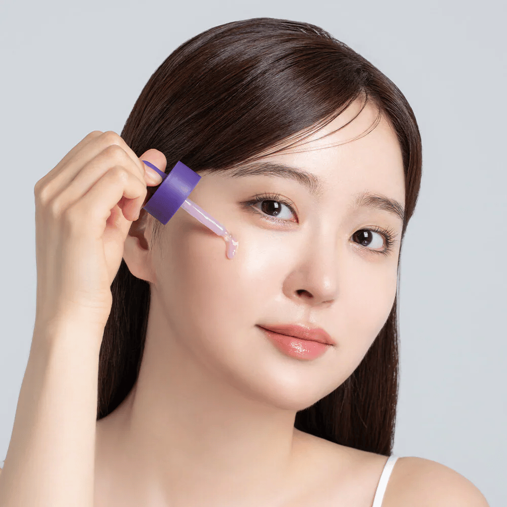 Application de Cellology Purple Carrot Pore Ampoule avec pipette sur le visage pour le soin des pores et une texture de peau plus uniforme.