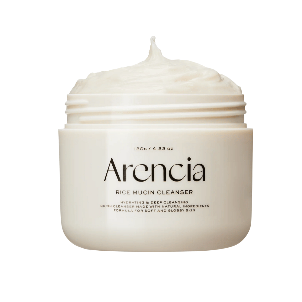 Image du produit sur Arencia Rice Mucin Cleanser dans un pot blanc avec une texture crémeuse et fouettée qui dépasse de l'ouverture. Le texte sur l'emballage met l'accent sur l'hydratation et le nettoyage en profondeur.