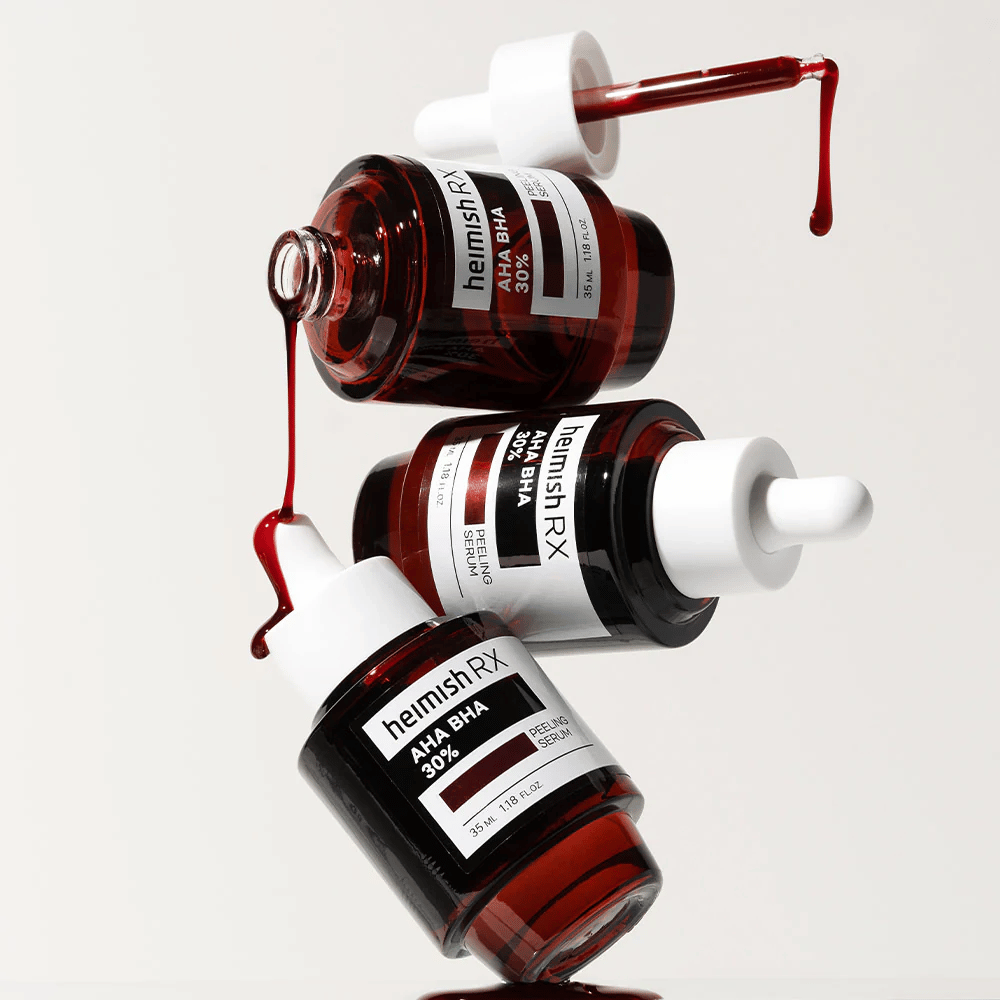 Trois bouteilles de Heimish RX AHA BHA 30% Peeling Serum dans une composition dynamique, avec du sérum rouge coulant des pipettes.