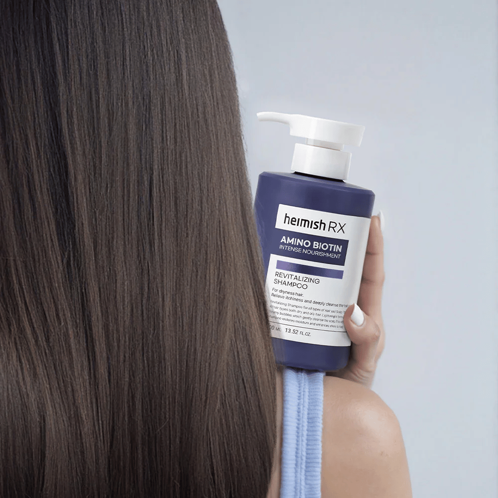 Heimish RX Amino Biotin Revitalizing Shampoo tenu dans la main contre des cheveux longs et brillants – montre le résultat d'une nutrition intensive et d'une hydratation pour les cheveux secs.