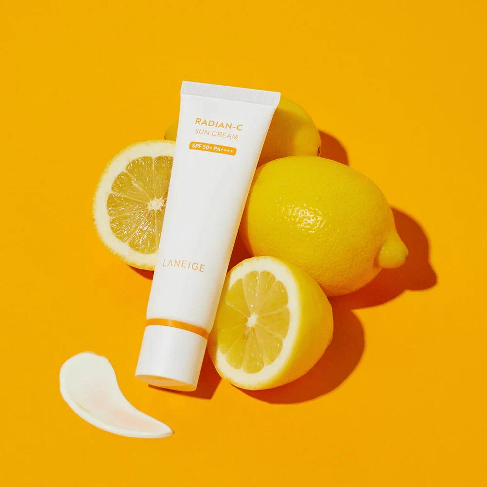 LANEIGE Radian-C Sun Cream SPF 50+ PA++++ avec des citrons et une noisette de crème solaire sur un fond jaune vif.
