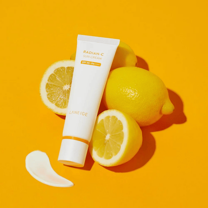 LANEIGE Radian-C Sun Cream SPF 50+ PA++++ avec des citrons et une noisette de crème solaire sur un fond jaune vif.