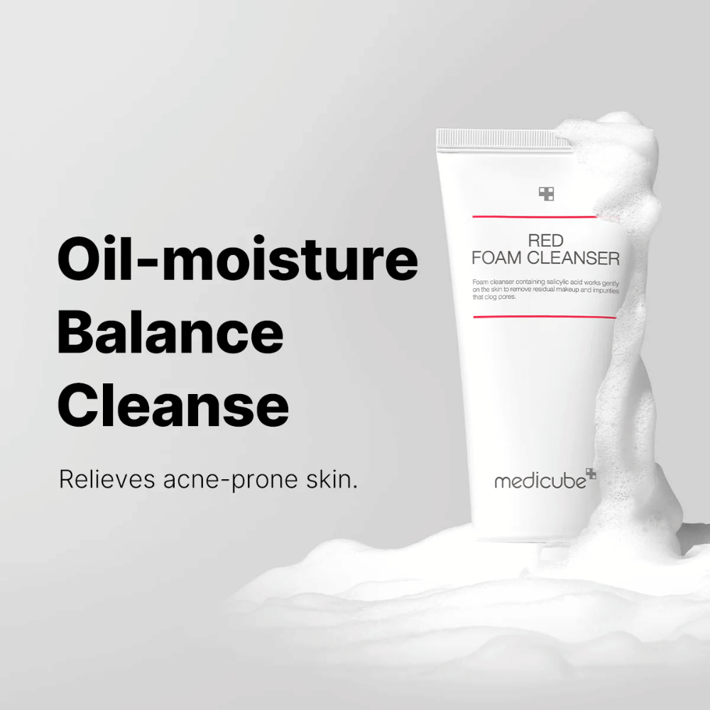 Tube avec Medicube Red Foam Cleanser debout parmi la mousse moussante. Le texte "Oil-moisture Balance Cleanse" est affiché à gauche, avec la description "Relieves acne-prone skin" en dessous. Le fond est gris clair.