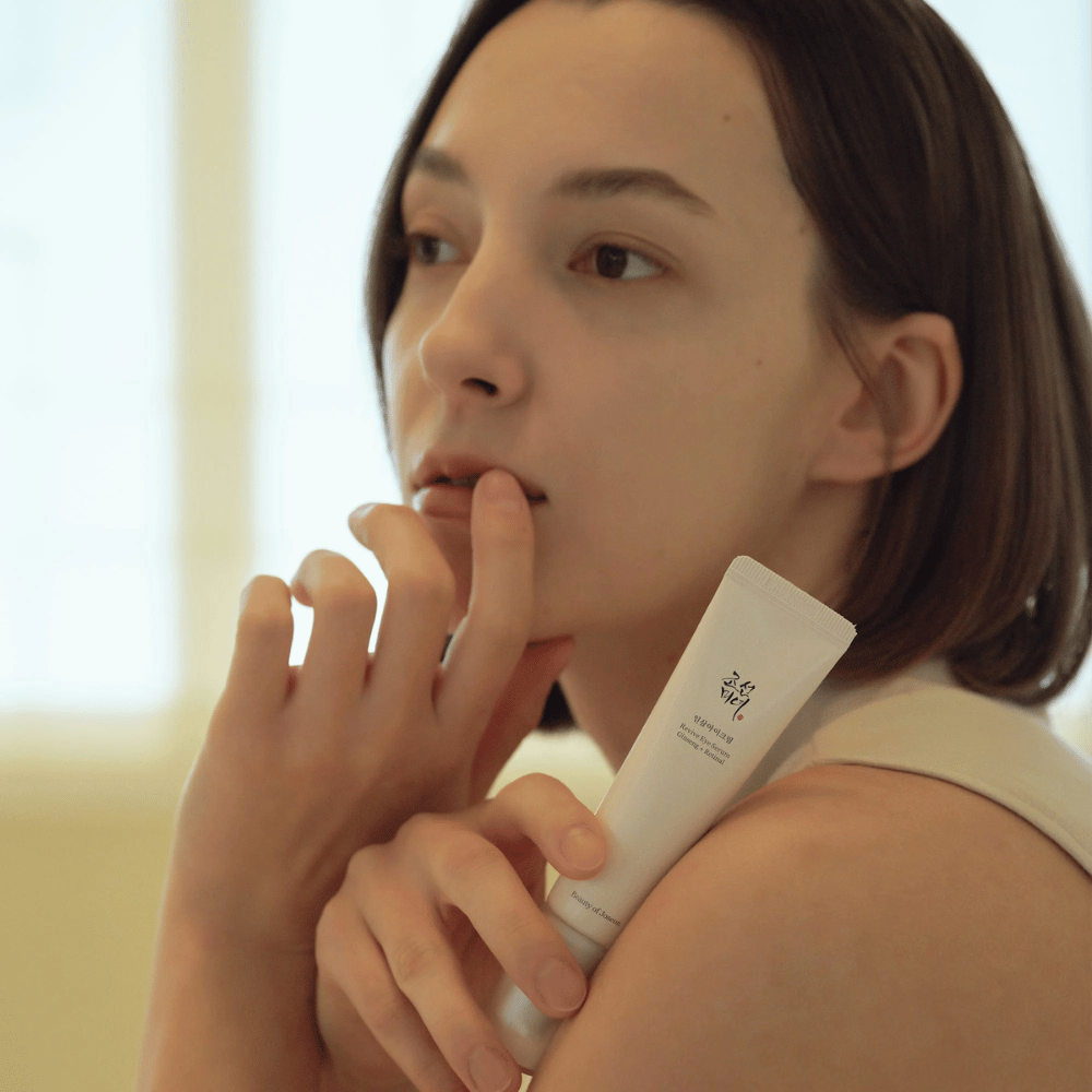 Le modèle tient Beauty of Joseon Revive Eye Serum et applique délicatement sur la peau pour un contour des yeux hydraté et lisse.