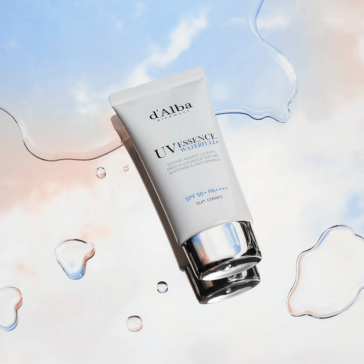 Image produit de d'Alba UV Essence Waterfull+ Sun Cream avec SPF 50+ PA++++, placé sur un fond avec des éclaboussures d'eau et un ciel bleu-rose – symbolise une protection solaire légère et hydratante.