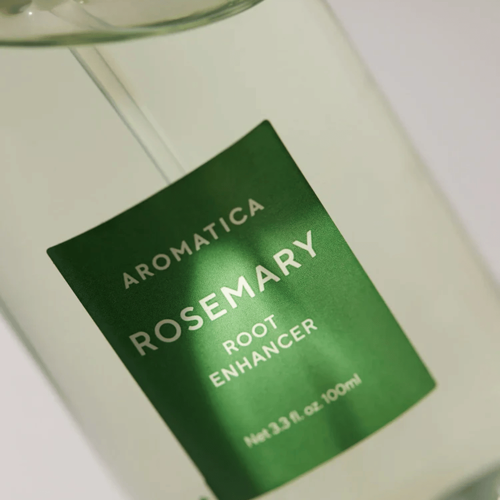 Gros plan de l’étiquette de AROMATICA Rosemary Root Enhancer. L’étiquette verte et la bouteille transparente mettent en valeur l’apparence propre et minimaliste du produit.