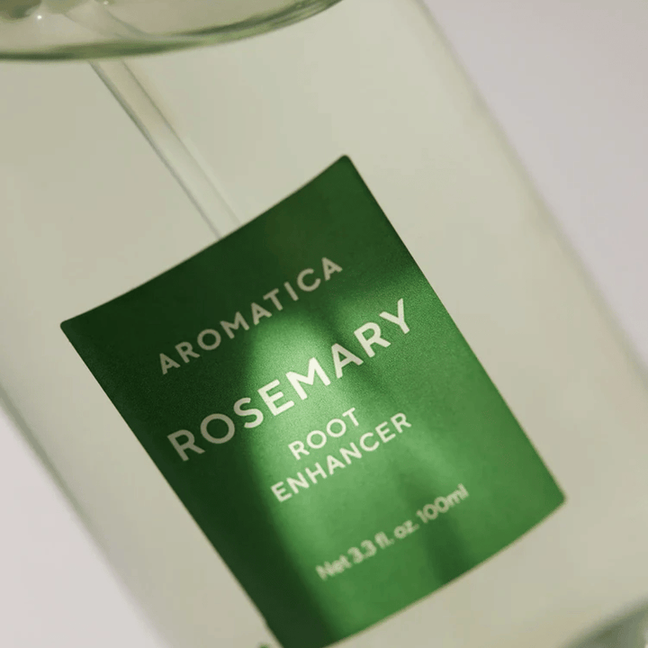 Gros plan de l’étiquette de AROMATICA Rosemary Root Enhancer. L’étiquette verte et la bouteille transparente mettent en valeur l’apparence propre et minimaliste du produit.
