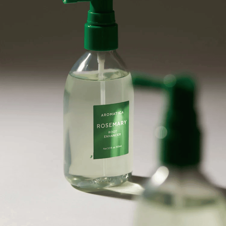 Gros plan de AROMATICA Rosemary Root Enhancer avec un embout applicateur vert. L’image se concentre sur le design de la bouteille et l’application précise directement sur le cuir chevelu.