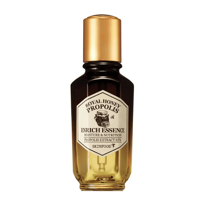 Image d'une bouteille en verre avec un liquide sombre et un bouchon doré. Sur l'étiquette de la bouteille est écrit "Royal Honey Propolis Enrich Essence" suivi de "Moisture & Nutrition" et "Propolis Extract 63%". La marque "Skinfood" apparaît également en bas de l'étiquette.