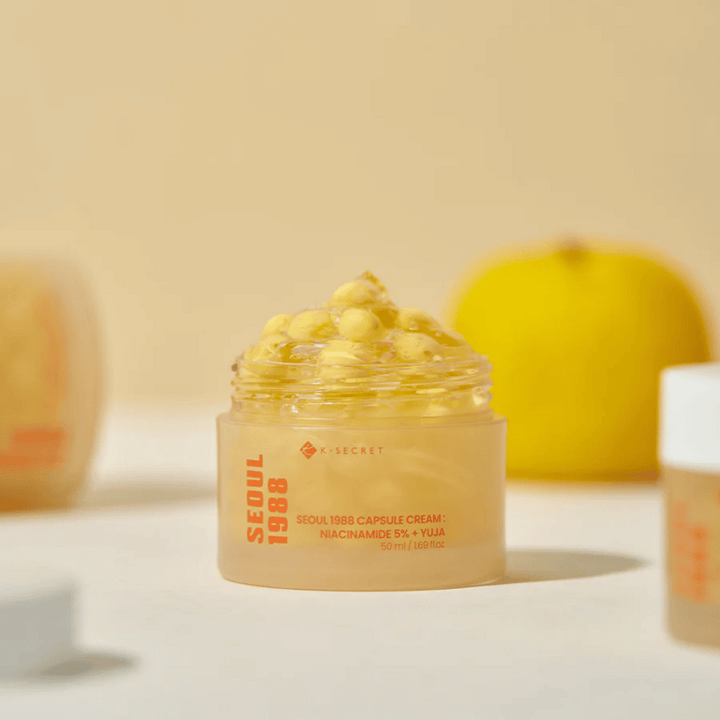Pot ouvert avec des capsules jaunes à côté d'un fruit de yuja coupé en deux qui met en valeur la formule riche en vitamine C.