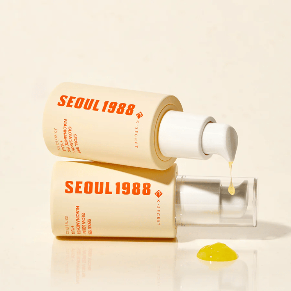 Deux bouteilles Séoul 1988 Glow Serum couchées et debout, avec du sérum jaune s'écoulant de la pompe.