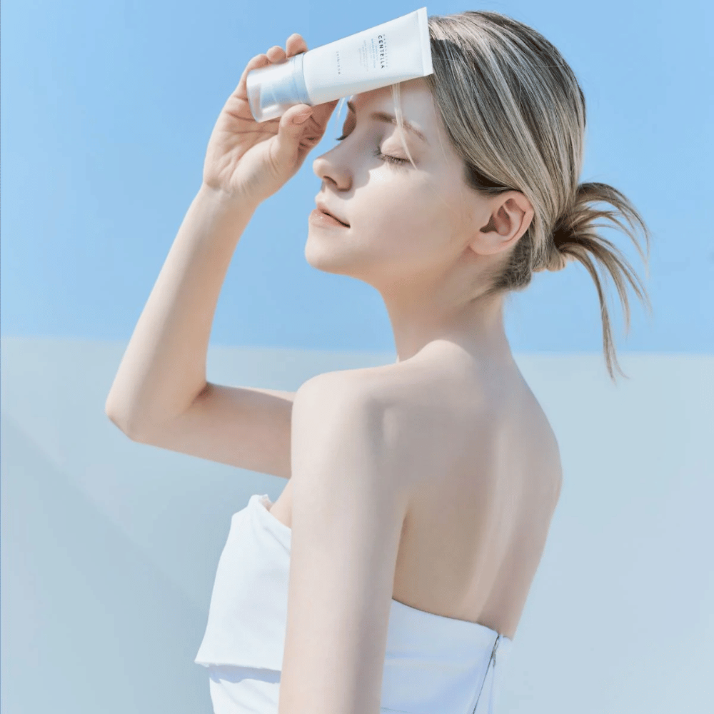 Une femme applique SKIN1004 Madagascar Centella Hyalu-Cica Water-Fit Sun Serum 50ml pour protéger le visage des rayons UV.