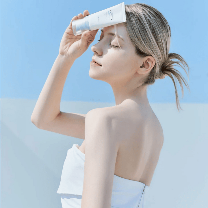 Une femme applique SKIN1004 Madagascar Centella Hyalu-Cica Water-Fit Sun Serum 50ml pour protéger le visage des rayons UV.