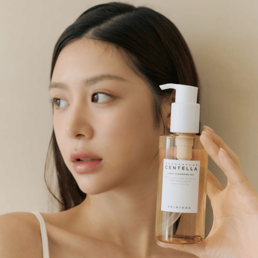 Une femme tenant une bouteille SKIN1004 Madagascar Centella Light Cleansing Oil 200 ml de nettoyant pour le visage.